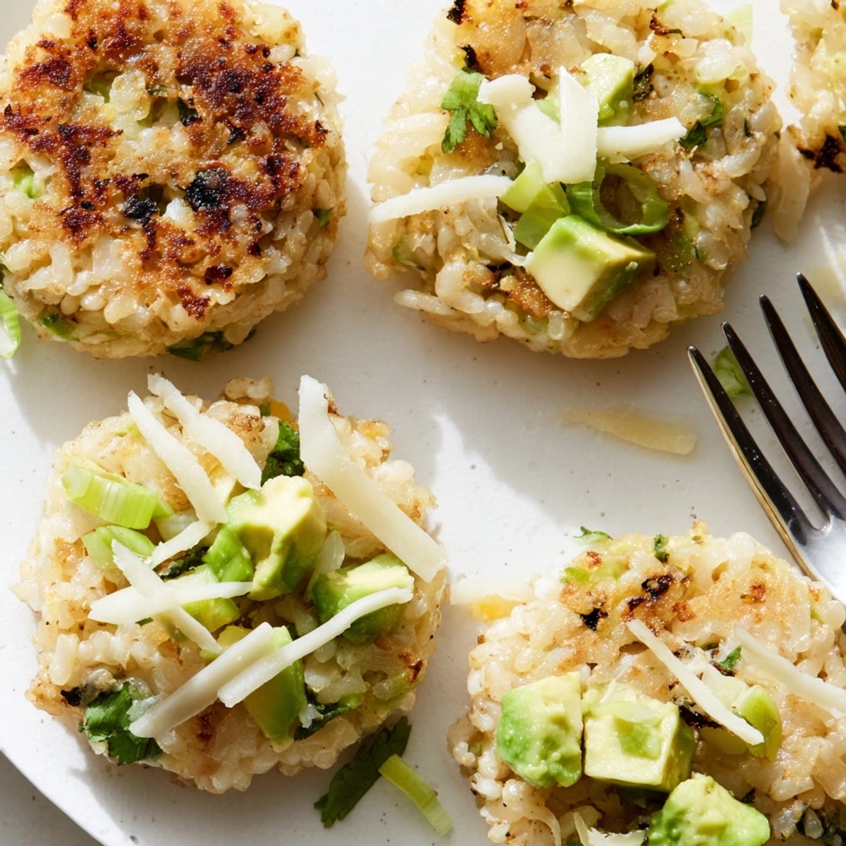 Crispy fried Avocado Cheddar Rice Cakes cooling, vibrant with green onion and herbs.