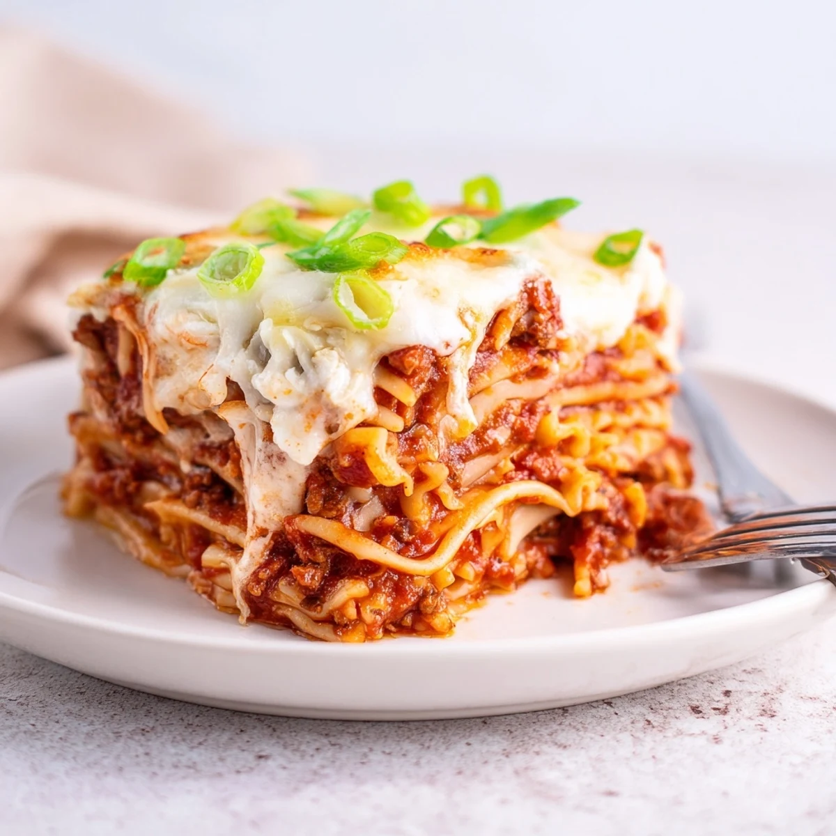 A comforting slice of spicy ramen lasagna showcasing vibrant meat sauce and creamy cheese.  