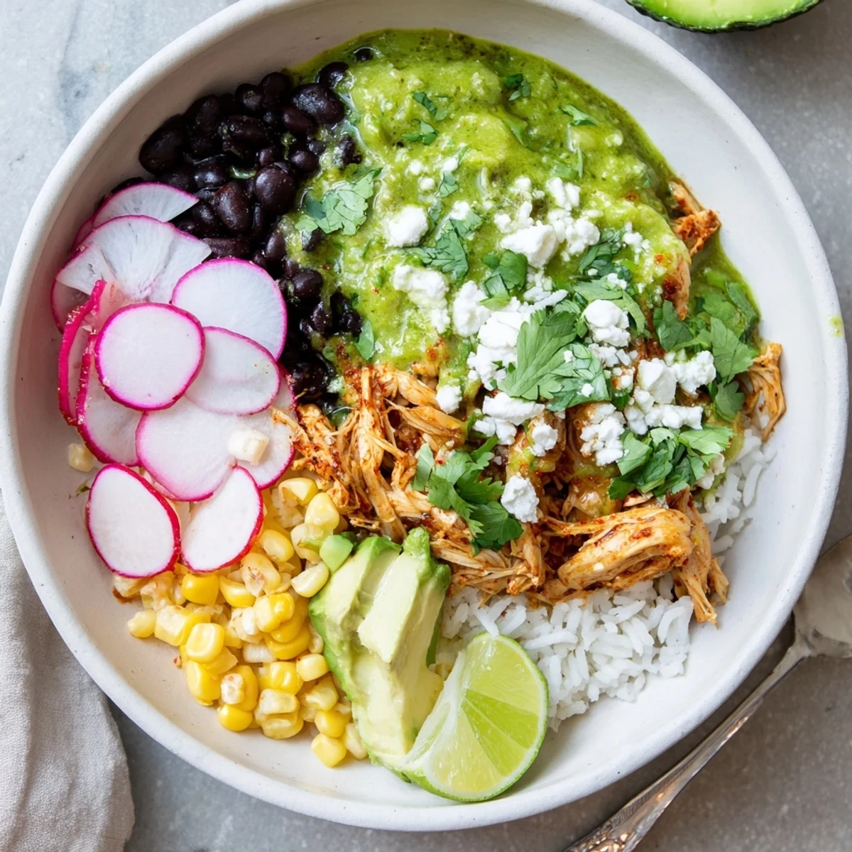 Colorful Green Enchiladas Rice Bowl garnished with queso fresco and lime wedges for added zest.