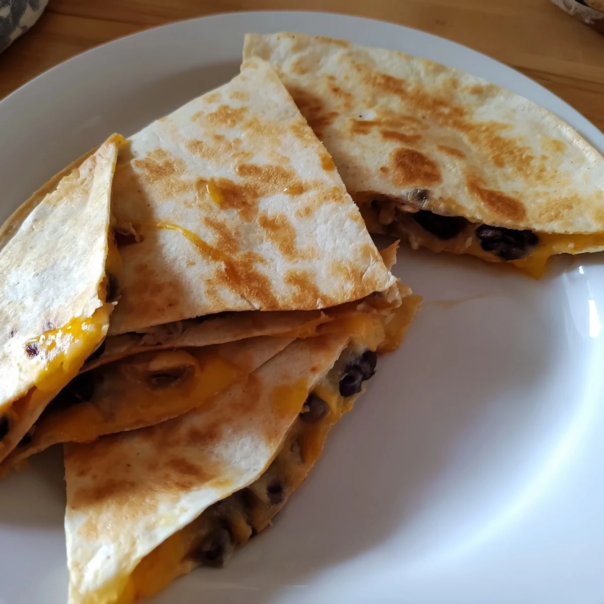 Warm, folded Bean & Cheese Quesadilla, perfectly browned and cut into wedges, ready to eat with toppings.