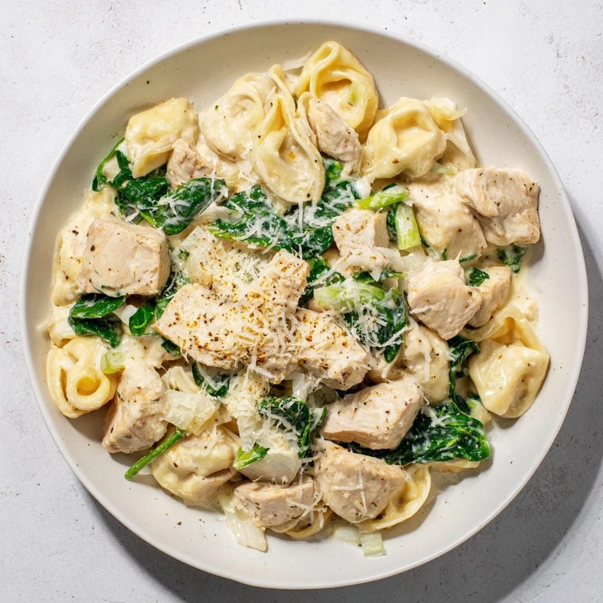 Creamy Chicken and Spinach Tortellini, a rich pasta dish, ready to savor with extra Parmesan cheese.
