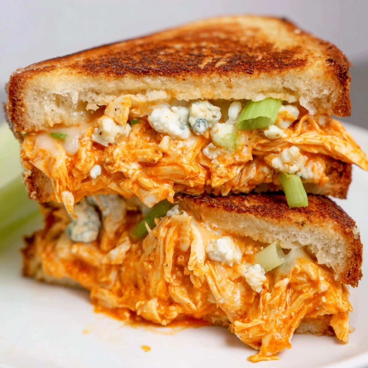 Hot, melty Buffalo Chicken Grilled Cheese on a plate, ready to be cut and savored.