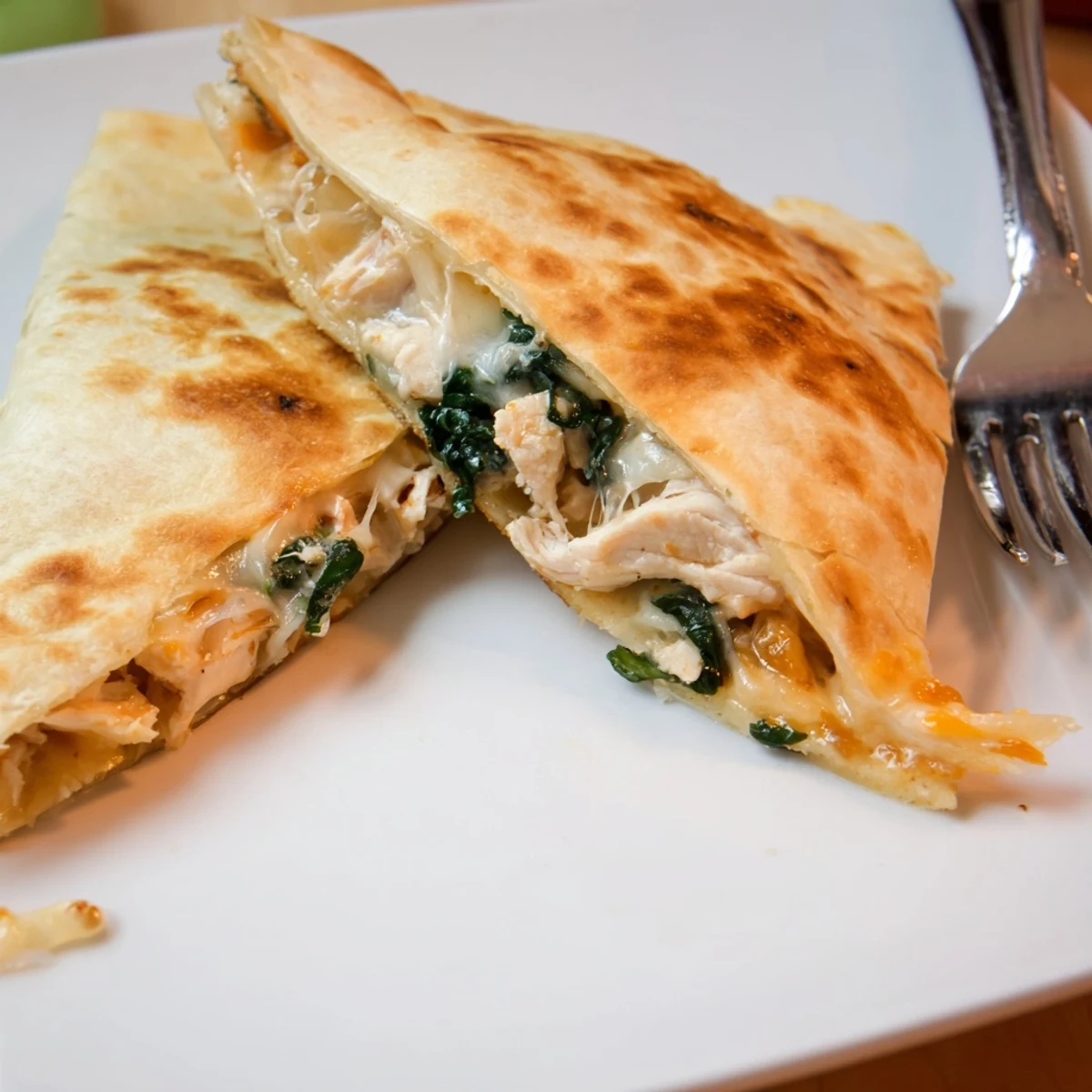 Warm Chicken and Spinach Quesadilla on a rustic plate, garnished with cilantro and a dollop of sour cream.