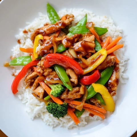 Steaming Chicken Stir-Fry with Vegetables and Rice, a colorful dish with savory sauce.