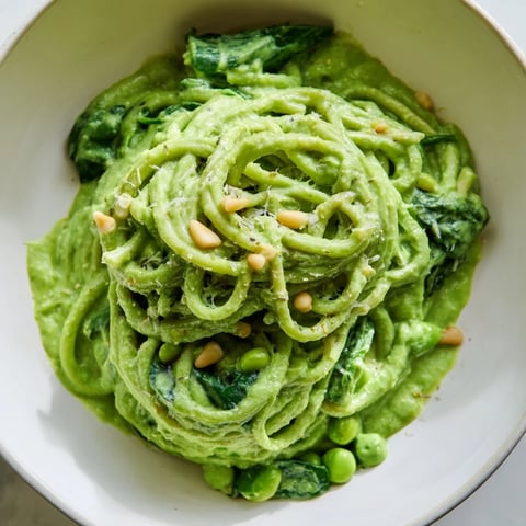A glossy bowl of Green Pea & Spinach Pasta, bright green sauce clinging to the protein pasta.