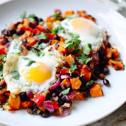 This skillet of colorful Sweet Potato & Black Bean Breakfast Hash features vibrant vegetables and perfectly cooked eggs.