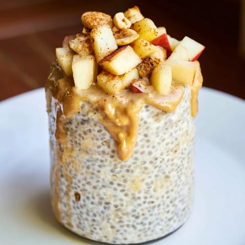 A close-up of layered Apple-Chia Pudding with Peanut Butter, showcasing fresh apples and a peanut butter swirl.