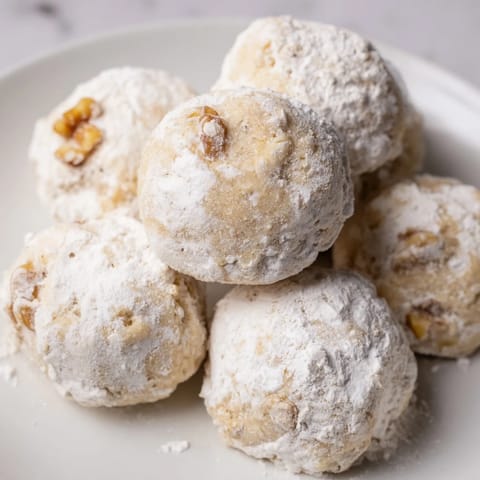 Warm, buttery Budget-Friendly Snowball Cookies, shown with their perfect, crumbly texture, ready to be devoured.