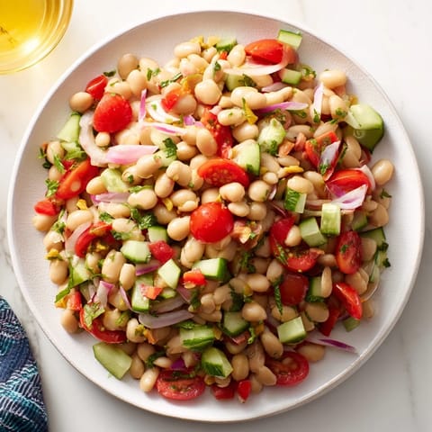 View a close-up of a refreshing Dense Bean Salad with Prosciutto, drizzled with zesty vinaigrette.