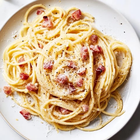 This close-up shows the delicious saucy texture of Express Spaghetti Carbonara sprinkled with fresh Parmesan cheese.