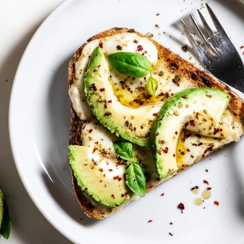 Golden, crispy bread holds a generous layer of mashed avocado and gooey mozzarella, broiled until bubbly and garnished with red pepper flakes in this vibrant Avocado Mozzarella Tartine.