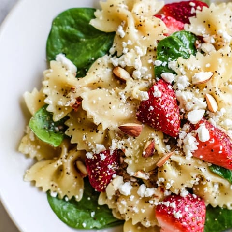 Spring Spinach Strawberry Pasta Salad served chilled, featuring tender farfalle pasta, sweet strawberries, crisp spinach, and toasted almonds for a refreshing lunch.