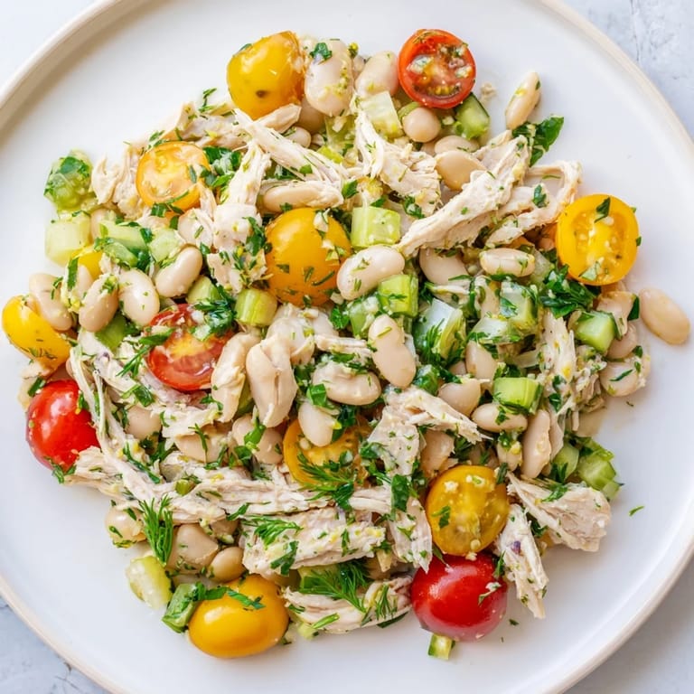 Close-up of Lemony White Bean Chicken Salad showing juicy chicken, white beans, and herbs tossed in a glossy lemon vinaigrette.